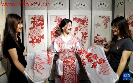 5月31日，在衡水市阜城县一家剪纸责任室，旅客在试穿带有剪纸元素的传统衣饰。